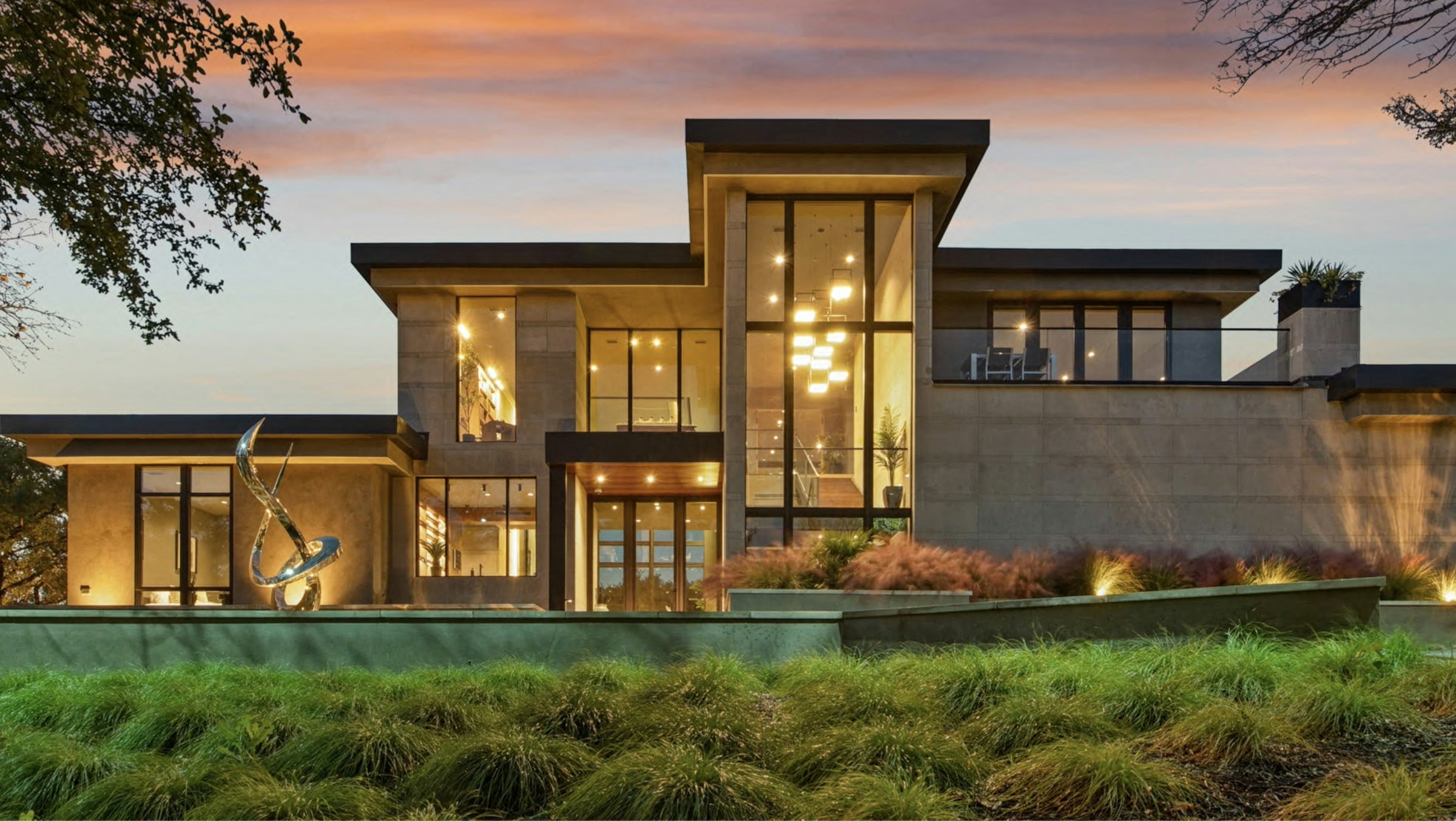 Modern luxury residence at dusk with warm interior light
